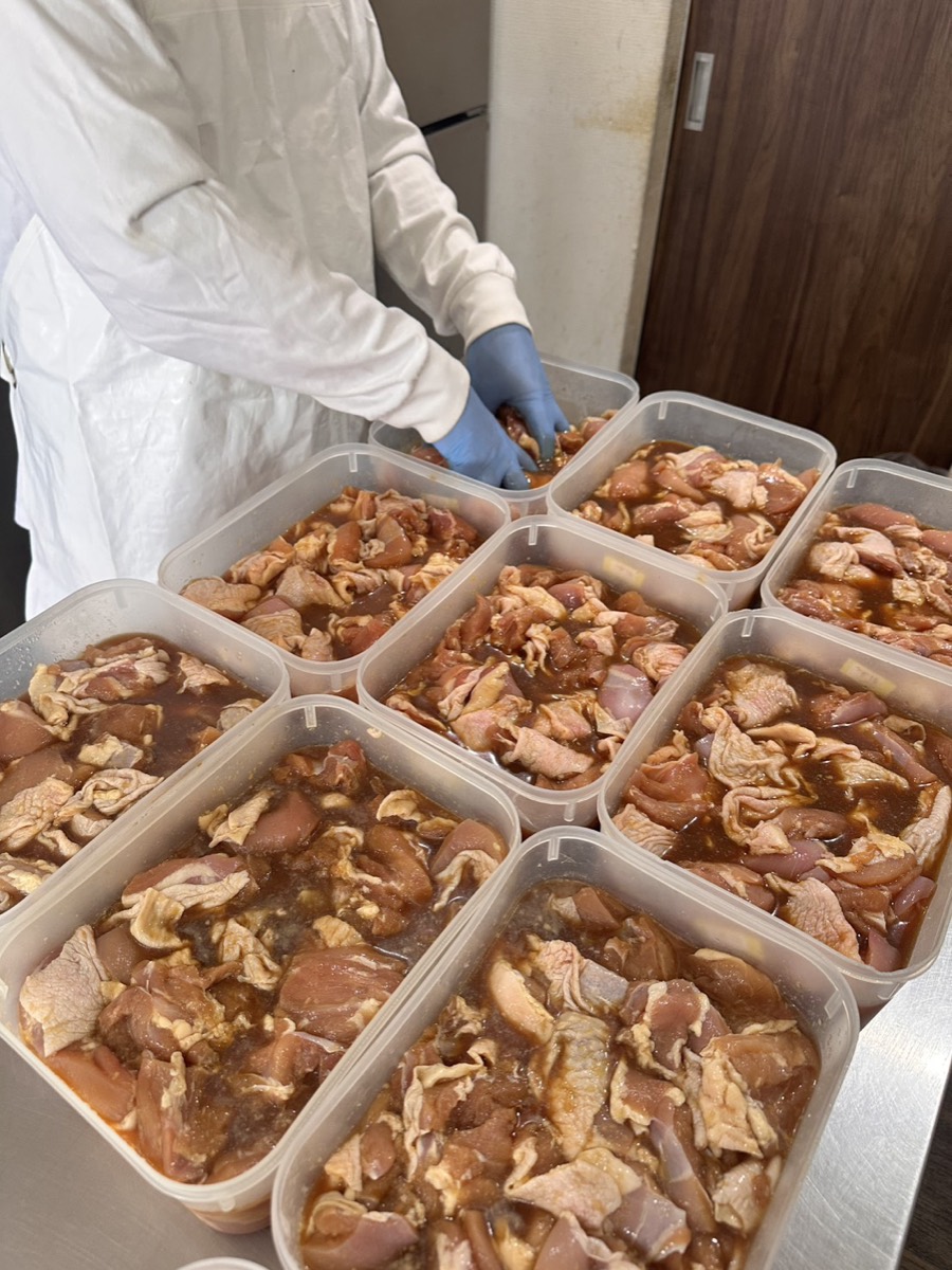タレに漬け込まれた鶏肉が、保存容器に整列して並んでいる仕込みの状態。