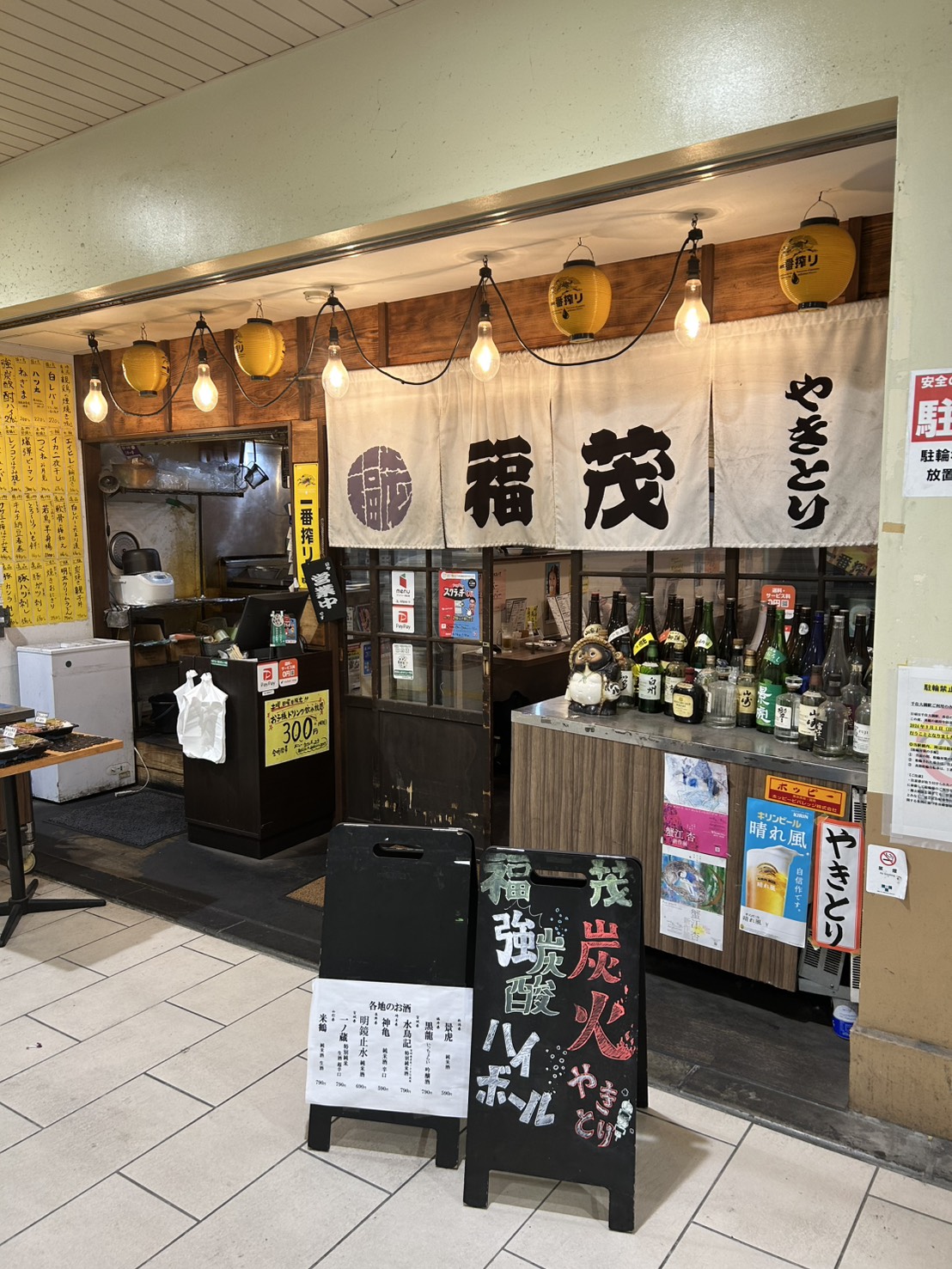 千住大橋店の店構え。「福茂」の暖簾と提灯、カウンター越しの炭火の焼き場