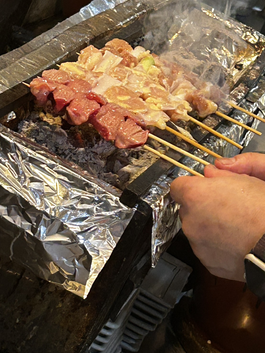 炭火に生串を並べる焼き場の手元