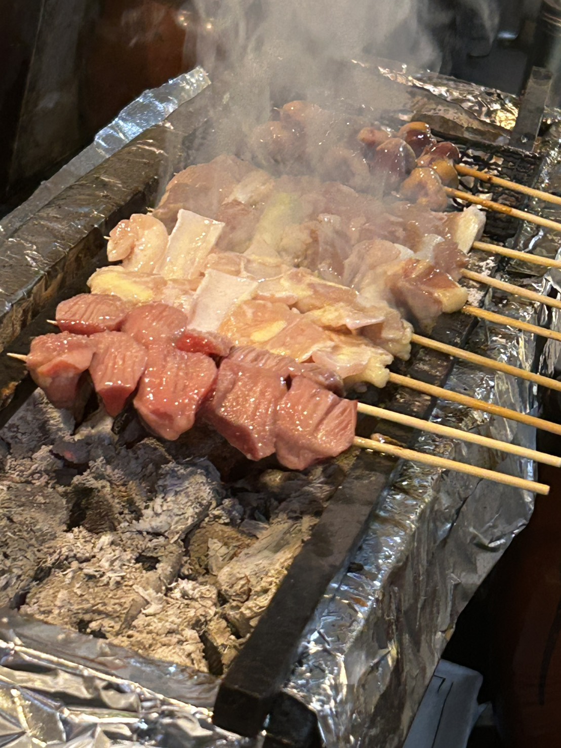 炭火で焼かれる串と立ちのぼる湯気